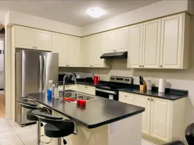 a kitchen with white cabinets and a stainless steel refrigerator at 15 mins from Niagara falls-5 Bedrooms Inn in Thorold