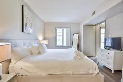 a white bedroom with a large bed and a television at Highland Hideaway 1BR King Suite in Shanty Bay