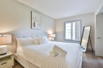 a bedroom with a large white bed and a mirror at Highland Hideaway 1BR King Suite in Shanty Bay