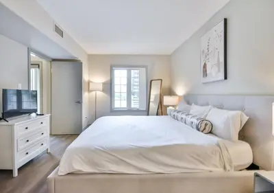 a bedroom with a large white bed and a television at King Suite heated Pool Sauna and Kitchen in Shanty Bay