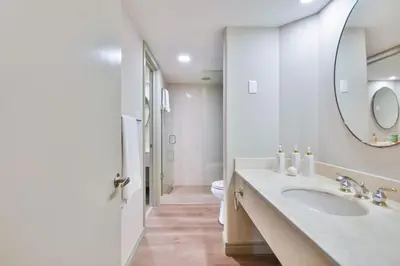 a white bathroom with a sink and a mirror at King Suite heated Pool Sauna and Kitchen in Shanty Bay