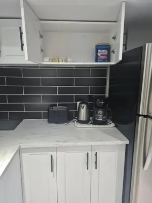 a kitchen with white cabinets and a black wall at Whitby one bedroom apartment in Whitby