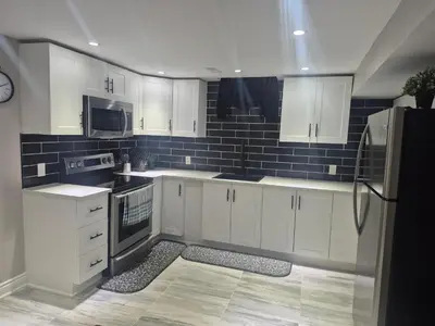 a kitchen with white cabinets and black appliances at Whitby one bedroom apartment in Whitby