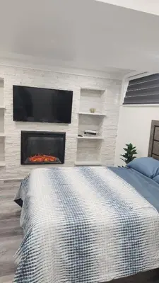 a bedroom with a fireplace with a tv on a wall at Entire Studio Guest Suite in Kitchener in Kitchener