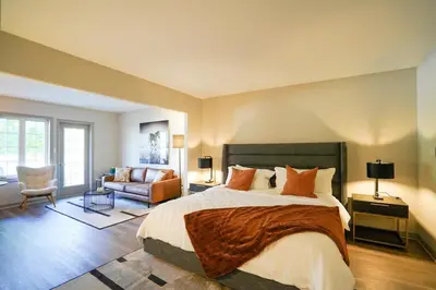 a bedroom with a large bed and a living room at Lower Level LuxSuite - 1min Walk from Heated Pool! in Shanty Bay