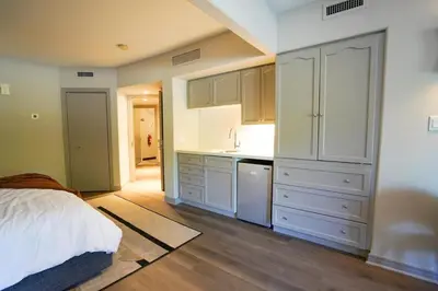 a kitchen with white cabinets and a bed in a room at Modern, fully renovated Studio! in Shanty Bay