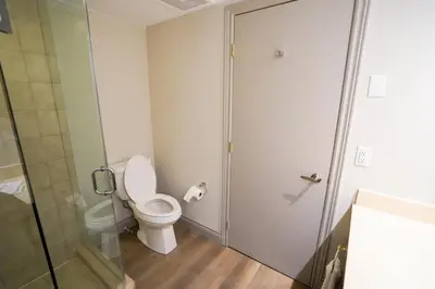 a bathroom with a toilet and a glass shower door at Modern, fully renovated Studio! in Shanty Bay