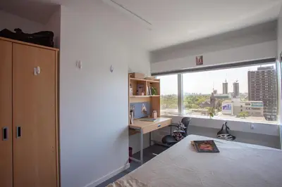 a bedroom with a bed and a desk and a window at Tartu College Student Residence in Toronto