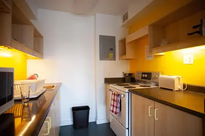 a kitchen with yellow walls and a stove top oven at Tartu College Student Residence in Toronto
