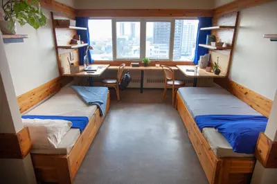 a dorm room with two beds and a desk at Tartu College Student Residence in Toronto
