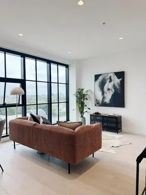 a living room with a brown couch in a room with windows at INFIVILLA King Suites & Towers Soho Toronto in Toronto