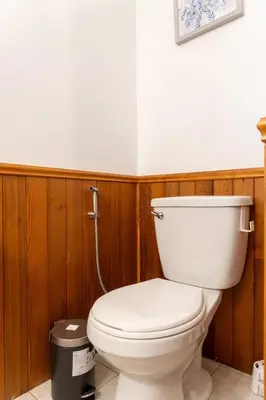 a white toilet in a bathroom with wooden walls at Luxurious waterfront cottage in Bowmanville