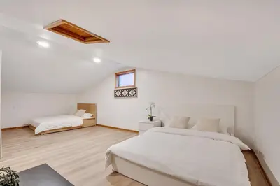 a white bedroom with two beds and a window at Luxurious waterfront cottage in Bowmanville
