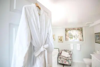a white robe hanging on a wall in a bathroom at The Jypsy Inn - The Royal Suite Bracebridge in Bracebridge