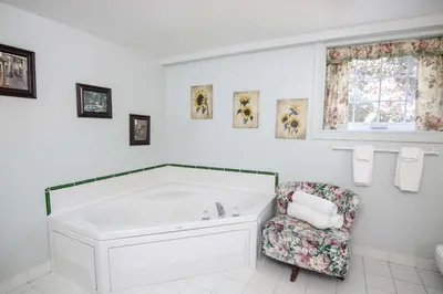 a white bathroom with a tub and a chair at The Jypsy Inn - The Royal Suite Bracebridge in Bracebridge