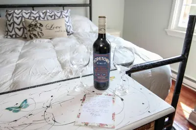 a bottle of wine and two wine glasses on a table at The Jypsy Inn - Tuxedo Room Muskoka in Bracebridge