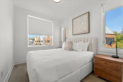 a white bedroom with a large bed and two windows at Luxury Muskoka Retreat in Gravenhurst