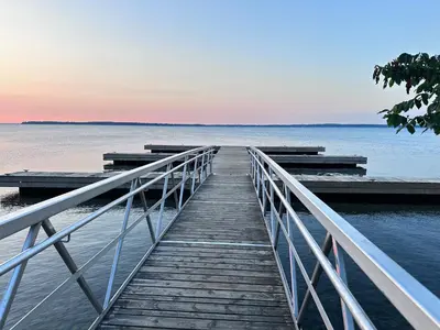 a wooden boardwalk leading into the water at sunset at Cozy 1BR Garden Suite Innisfil Beach Park in Innisfil