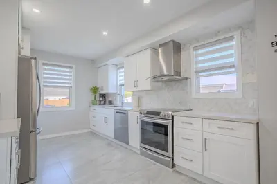 a white kitchen with white cabinets and windows at Wonderful house in Niagara on the Lake