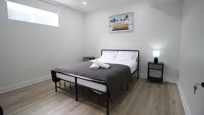 a bedroom with a bed in a white room at Beautiful Separate Unit, GrandRiver & Kiwanis Park in Kitchener
