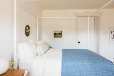 a white bedroom with a blue and white bed at Babcock-Hubbs House in Carrying Place