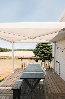 a wooden deck with a table and chairs under a tent at Babcock-Hubbs House in Carrying Place