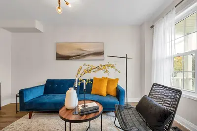 a living room with a blue couch and a table at Instaworthy Home - Relaxing Patio - Hot tub & BBQ in Cambridge