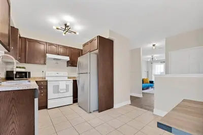 a kitchen with wooden cabinets and white appliances at Instaworthy Home - Relaxing Patio - Hot tub & BBQ in Cambridge