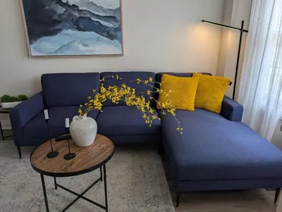 a blue couch with yellow pillows in a living room at Instaworthy Home - Relaxing Patio - Hot tub & BBQ in Cambridge