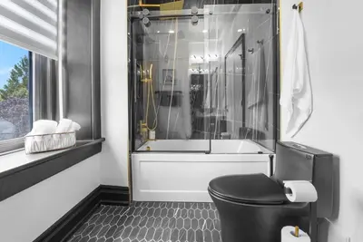 a bathroom with a black toilet and a shower at The Wynford Elora The Monroe Suite in Elora