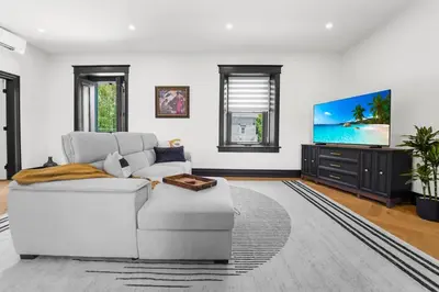 a living room with a white couch and a tv at The Wynford Elora The Monroe Suite in Elora