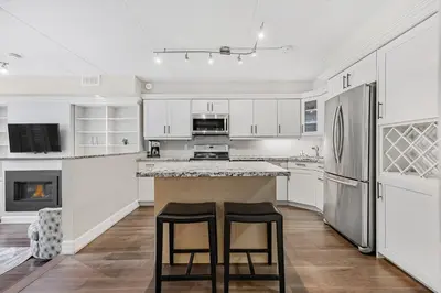 a kitchen with white cabinets and two bar stools at Blue Mountain Haus - Private Patio - Walk to Blue in Blue Mountains