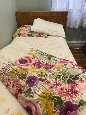a bed with a floral comforter on it at Peaceful and Private Room in Brampton