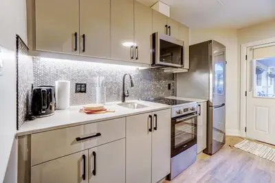 a kitchen with white cabinets and a sink at Adrian's Suites 1 Bedroom Junior Suite in Wasaga Beach