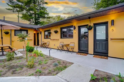 a yellow house with a table and chairs at Adrian's Suites 1Bedroom Junior Suite in Wasaga Beach