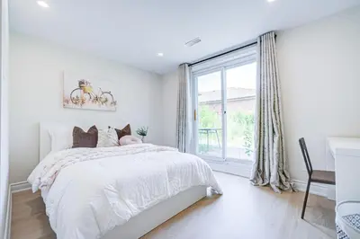 a white bedroom with a bed and a window at nest in orchard-main unit room in Toronto