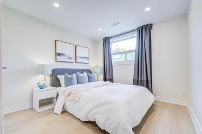 a white bedroom with a bed and a window at nest in orchard-main unit room in Toronto