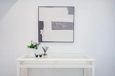 a white table with flowers and a picture on the wall at nest in orchard-main unit room in Toronto