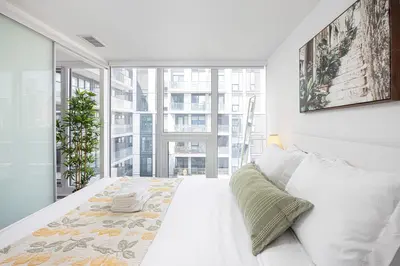 a bedroom with a white bed and a large window at 2br Luxury & Modern Suite 5 Minutes from Eaton Center in Toronto