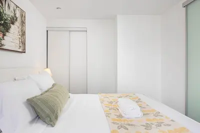 a bedroom with a white bed with a blanket on it at 2br Luxury & Modern Suite 5 Minutes from Eaton Center in Toronto