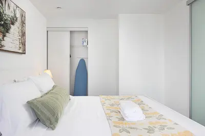 a bedroom with a white bed with a refrigerator at 2br Luxury & Modern Suite 5 Minutes from Eaton Center in Toronto