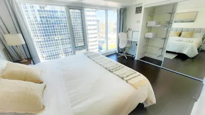 a bedroom with a large white bed and a mirror at Pantages Skyline Suite in Toronto Centre - Free Parking in Toronto