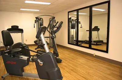 a gym with tread machines and a mirror at Staywell Inn & Suites in London