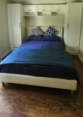 a bedroom with a large bed with blue sheets and pillows at Sunny Corner Room with View in Toronto