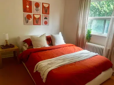 a bedroom with a red bed and a window at Cozy Upper Beaches Apartment in Toronto