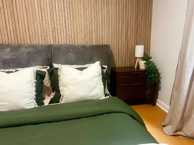 a bed with green and white pillows and a side table at Cozy Upper Beaches Apartment in Toronto