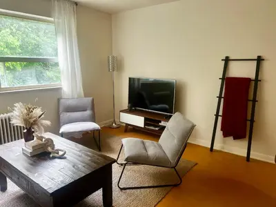 a living room with a tv and a table and chairs at Cozy Upper Beaches Apartment in Toronto