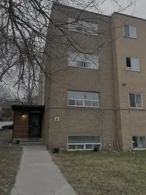 a large brick building with a door and a sidewalk at Cozy Upper Beaches Apartment in Toronto