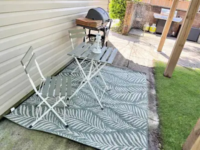 a table and chair sitting on a rug next to a house at Cozy Retreat with Netflix and Work Desk in Fort Erie