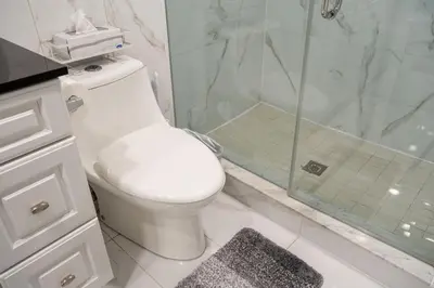 a white bathroom with a toilet and a shower at Stylish 2BR Home with Front Yard and Free Parking in Toronto